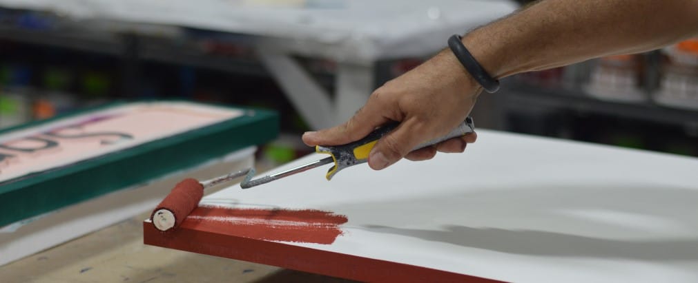 Sign being painted with roller in warehouse